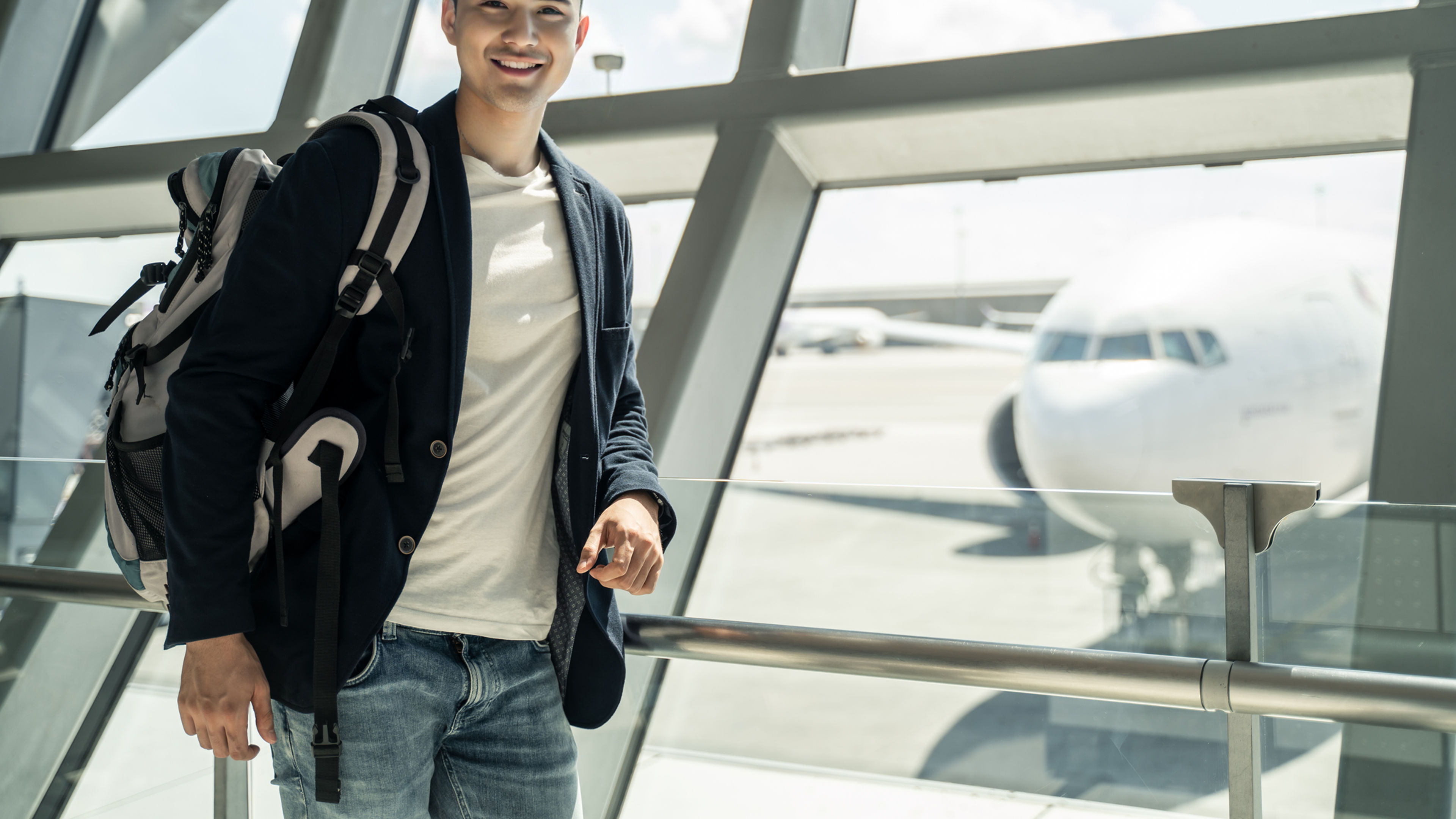 Asian boy waiting to board into airplane, standing in departure terminal in airport.