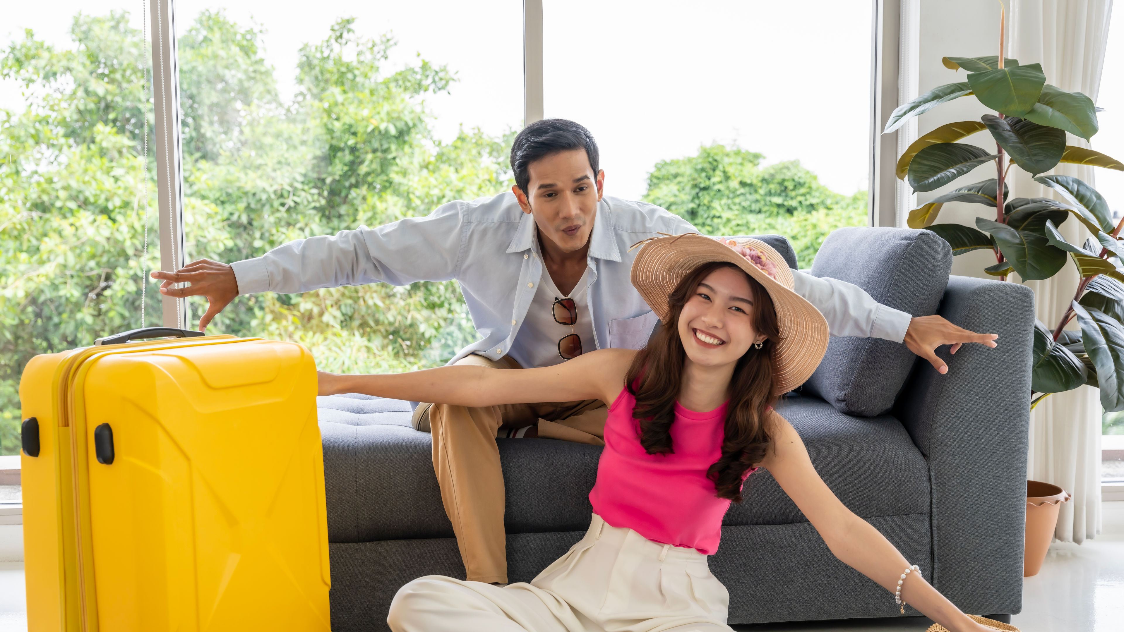 A joyful Asian couple posing next to a bright yellow trolley during their travels