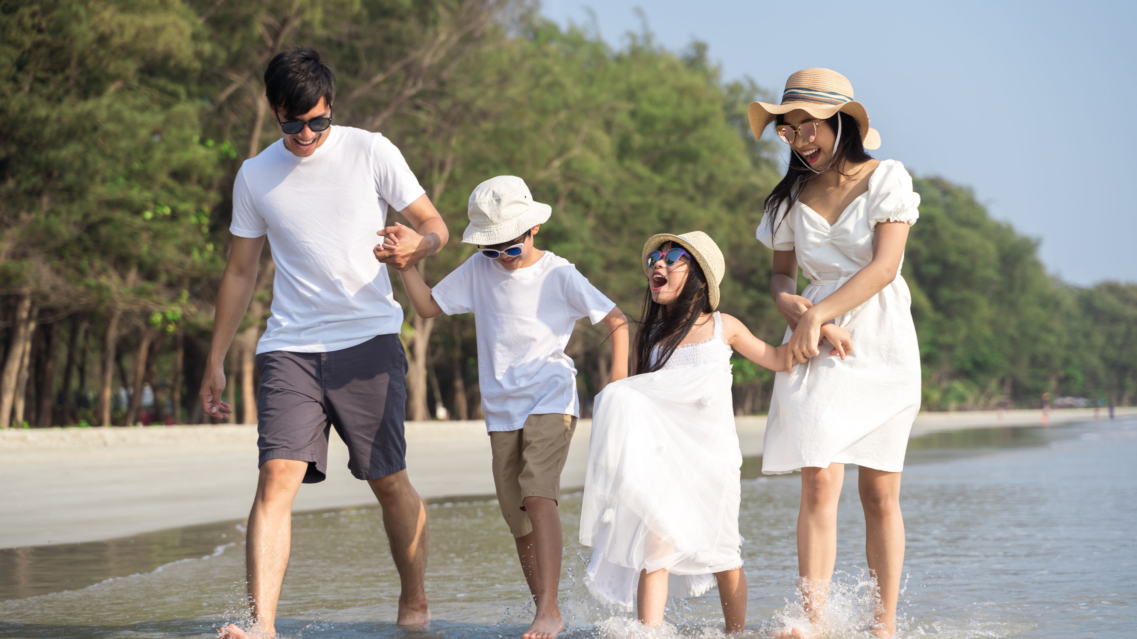 A happy family of four walks along the shore