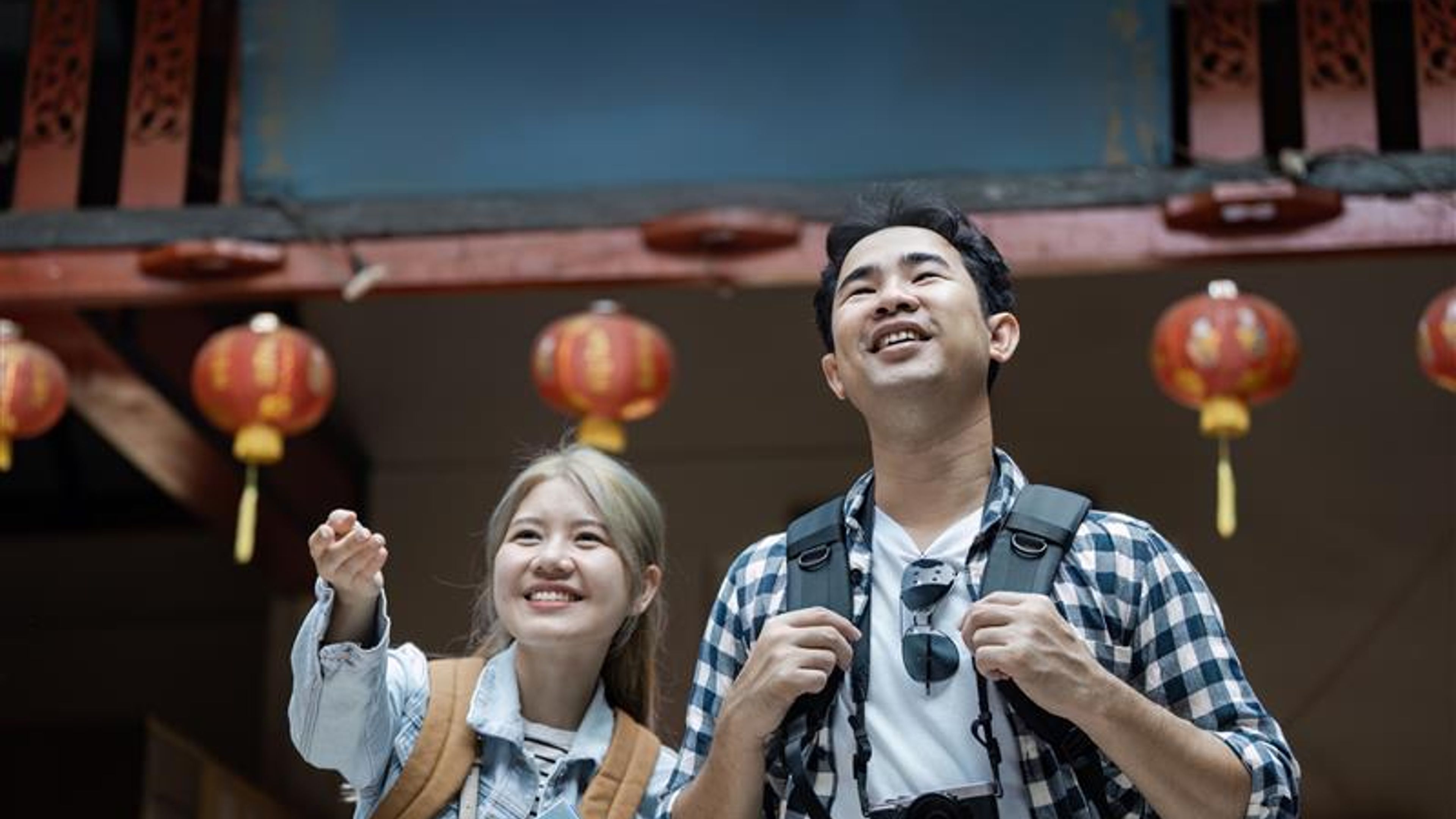 A joyful couple explores a historic temple adorned with vibrant lanterns the essence of travel and cultural discovery.