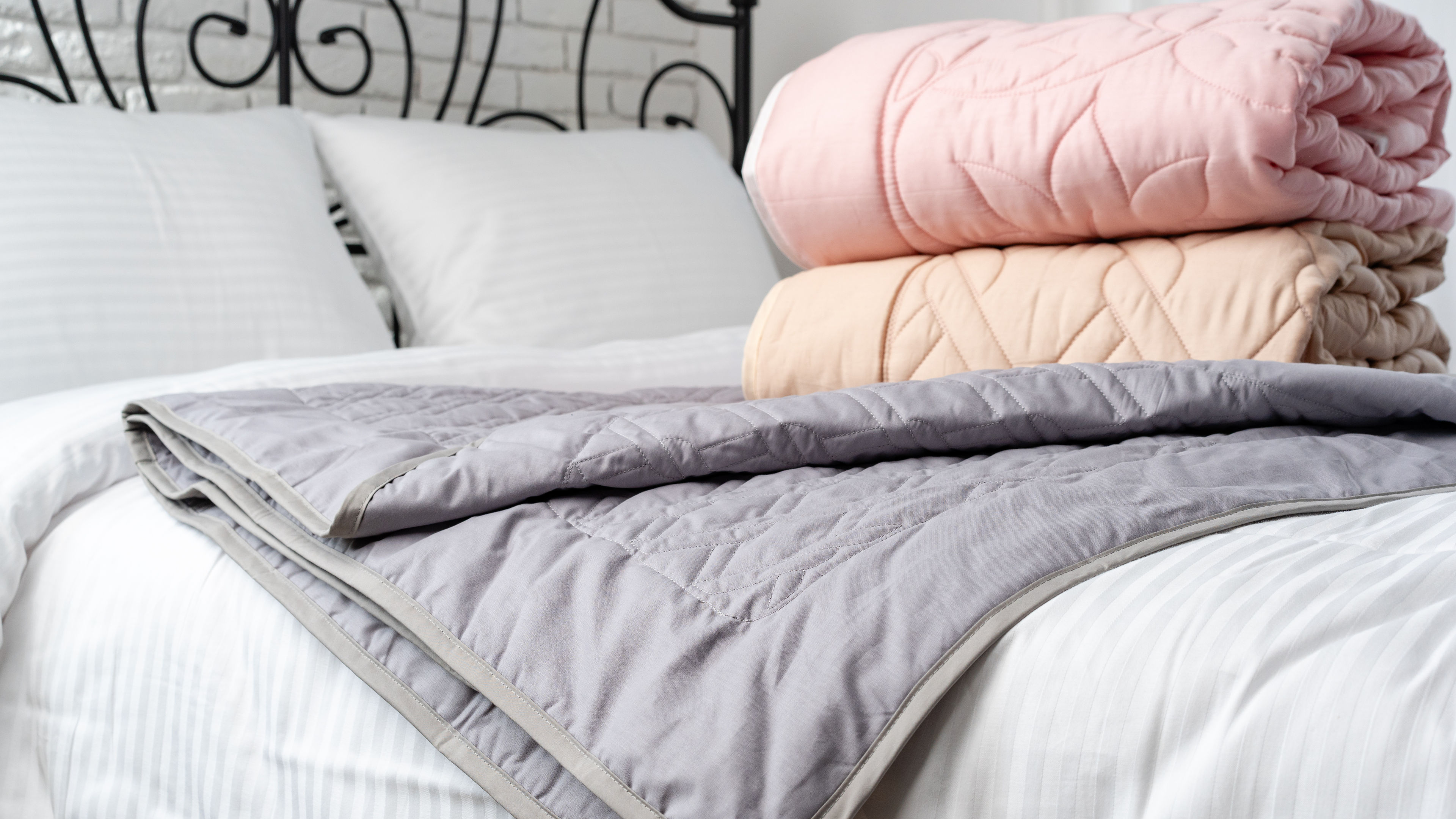 A neatly made bed with a white and grey striped sheet