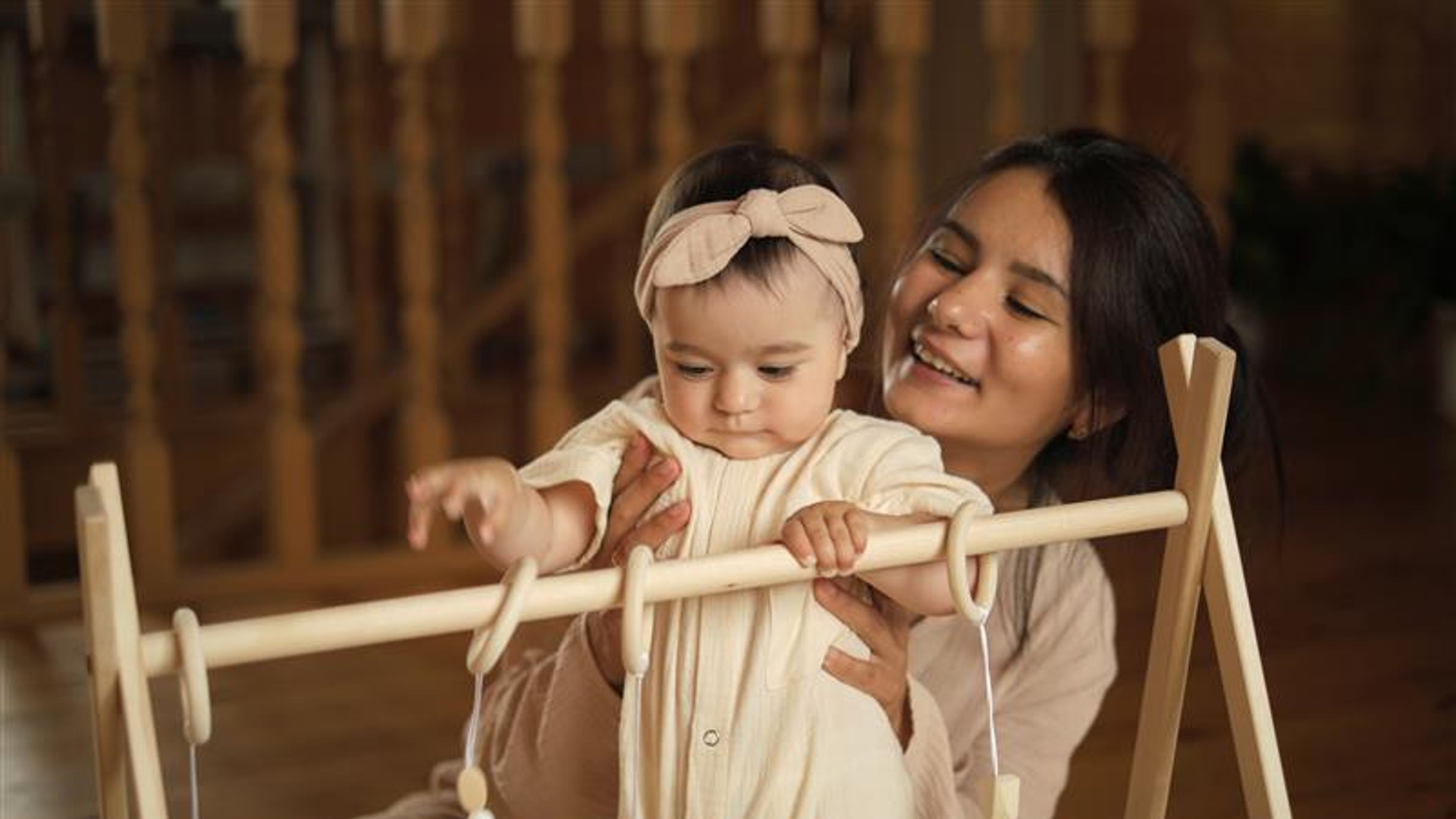 A tiny explorer examines hanging toys, a scene of innocence and exploration.