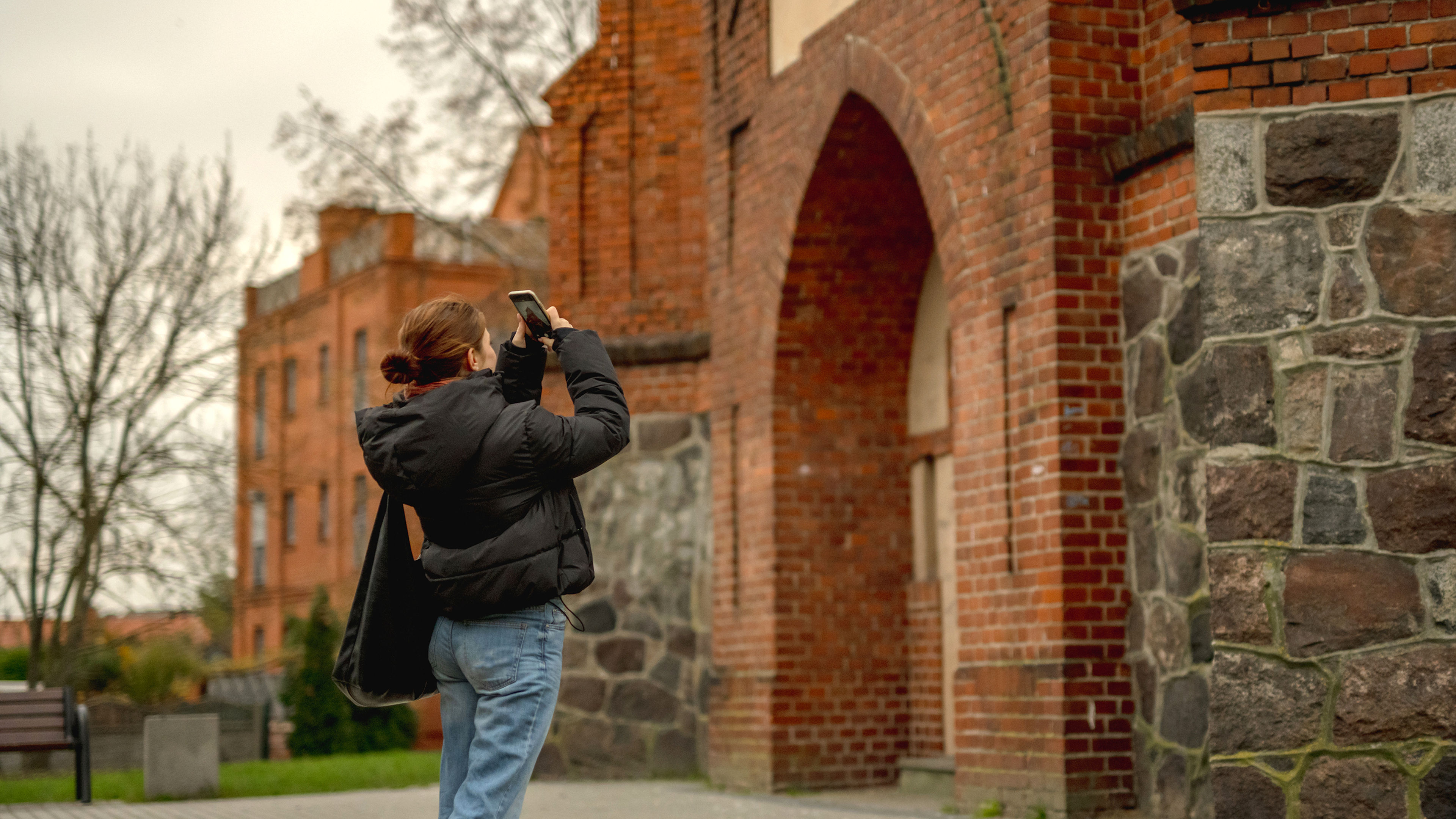 A woman is taking a photo of a historical building.