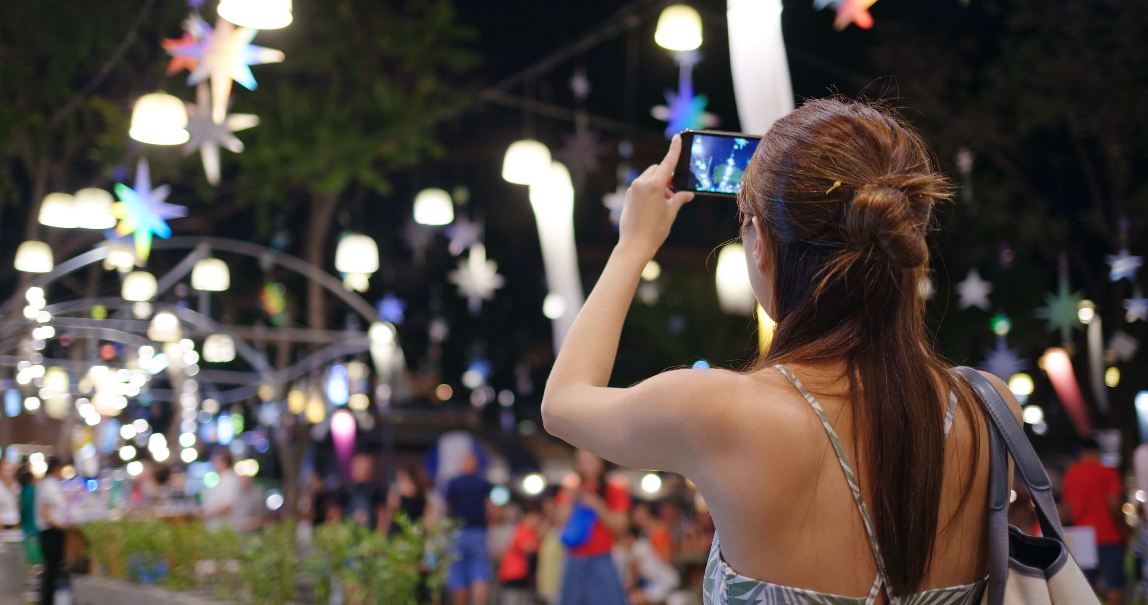 A woman takes a photo of a beautifully lit night market 