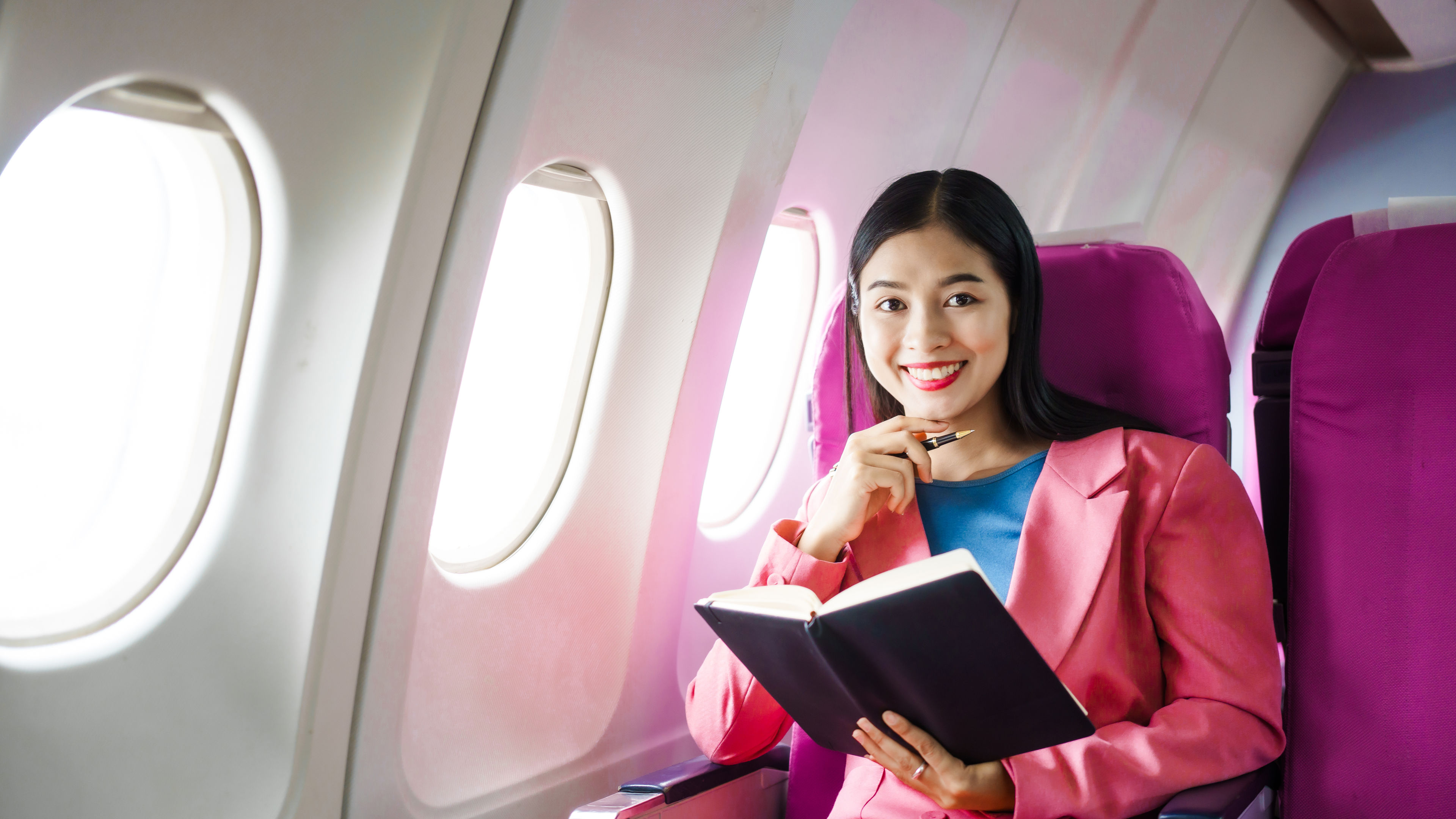 A young Asian female airplane passenger sits by the window during the flight. 