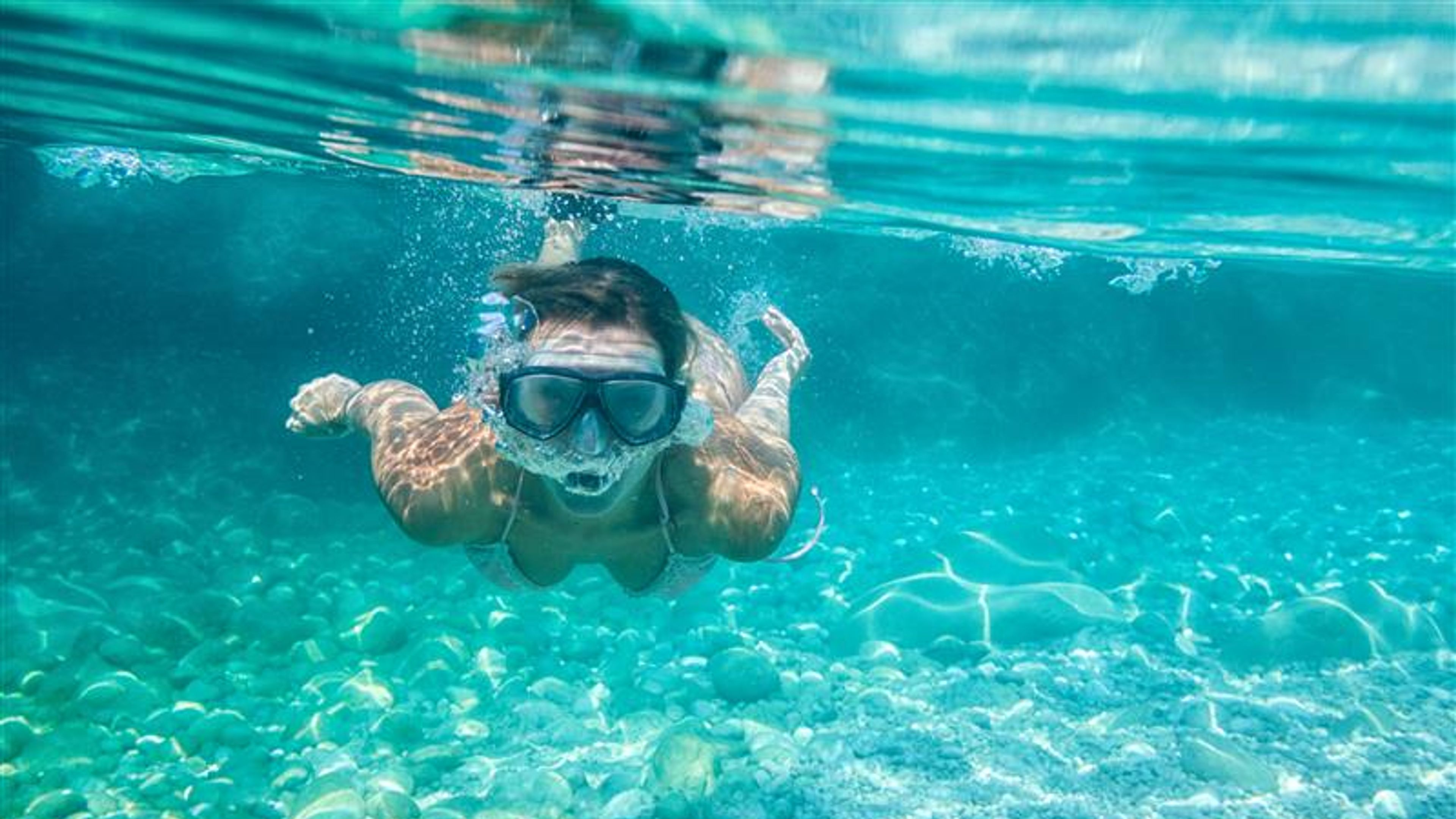 A young woman snorkelling under the sea.