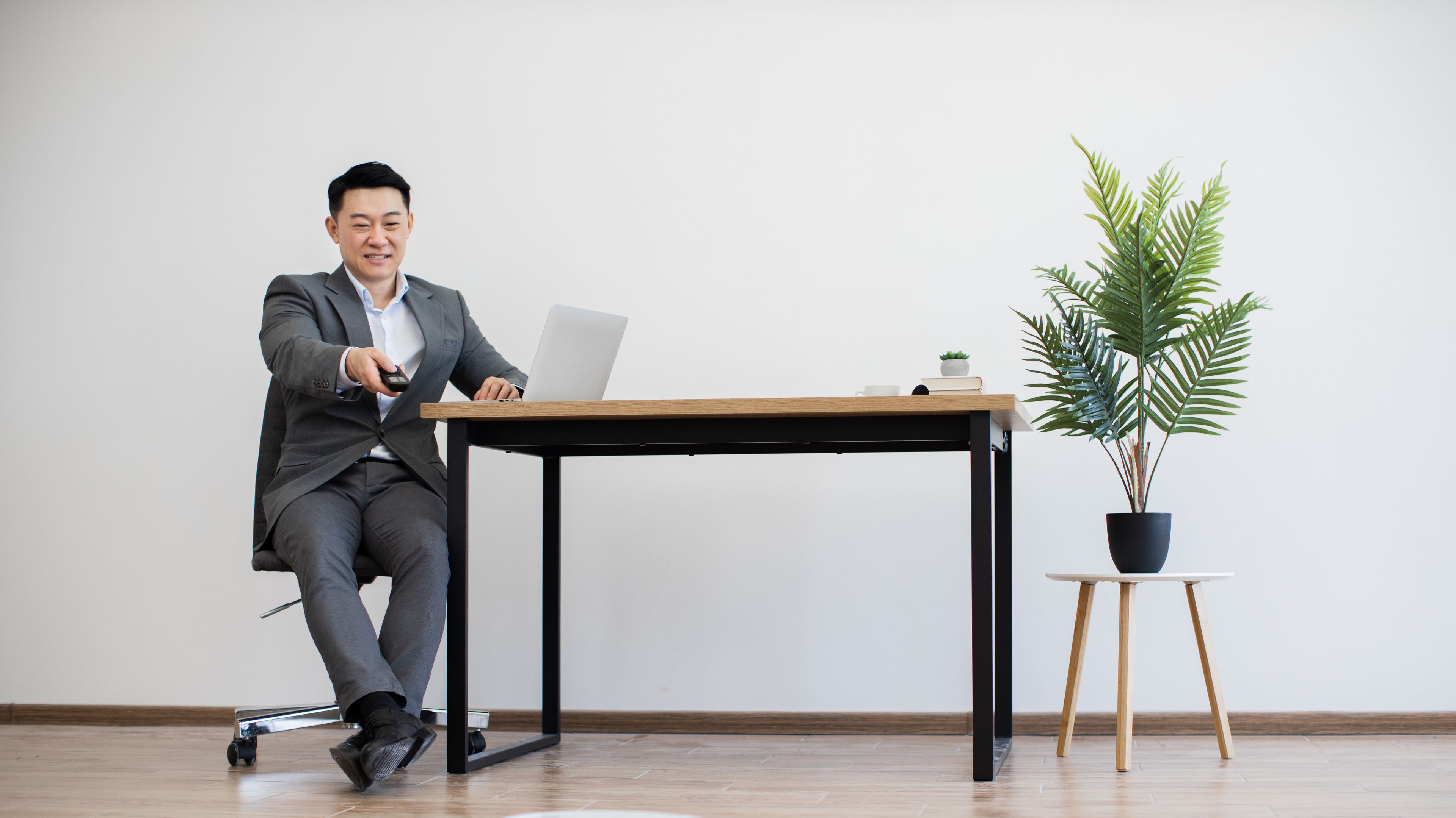 businessman controls robot vacuum while working on laptop.