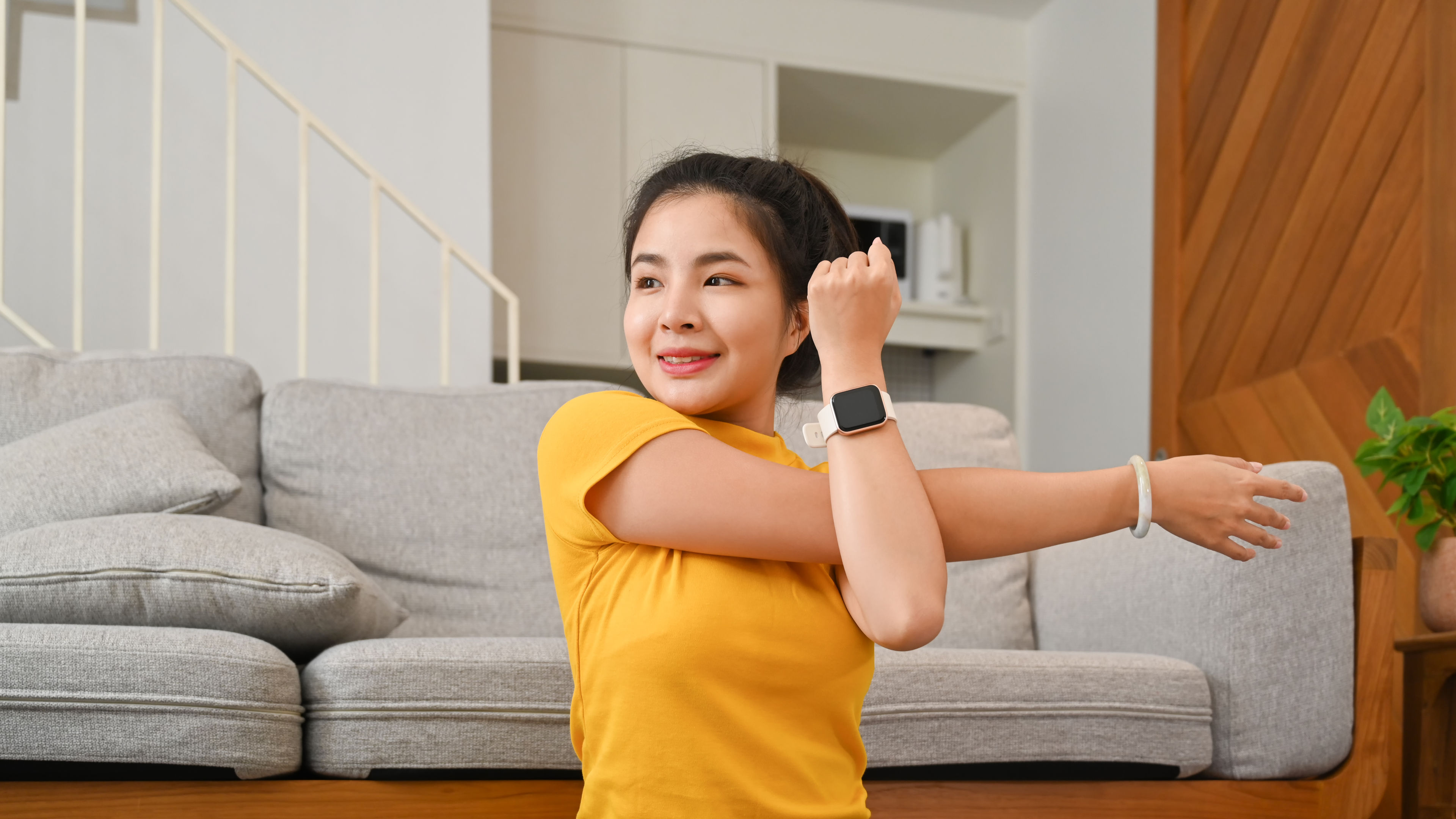 Charming asian woman doing stretching arm, warming up before workout at home. 