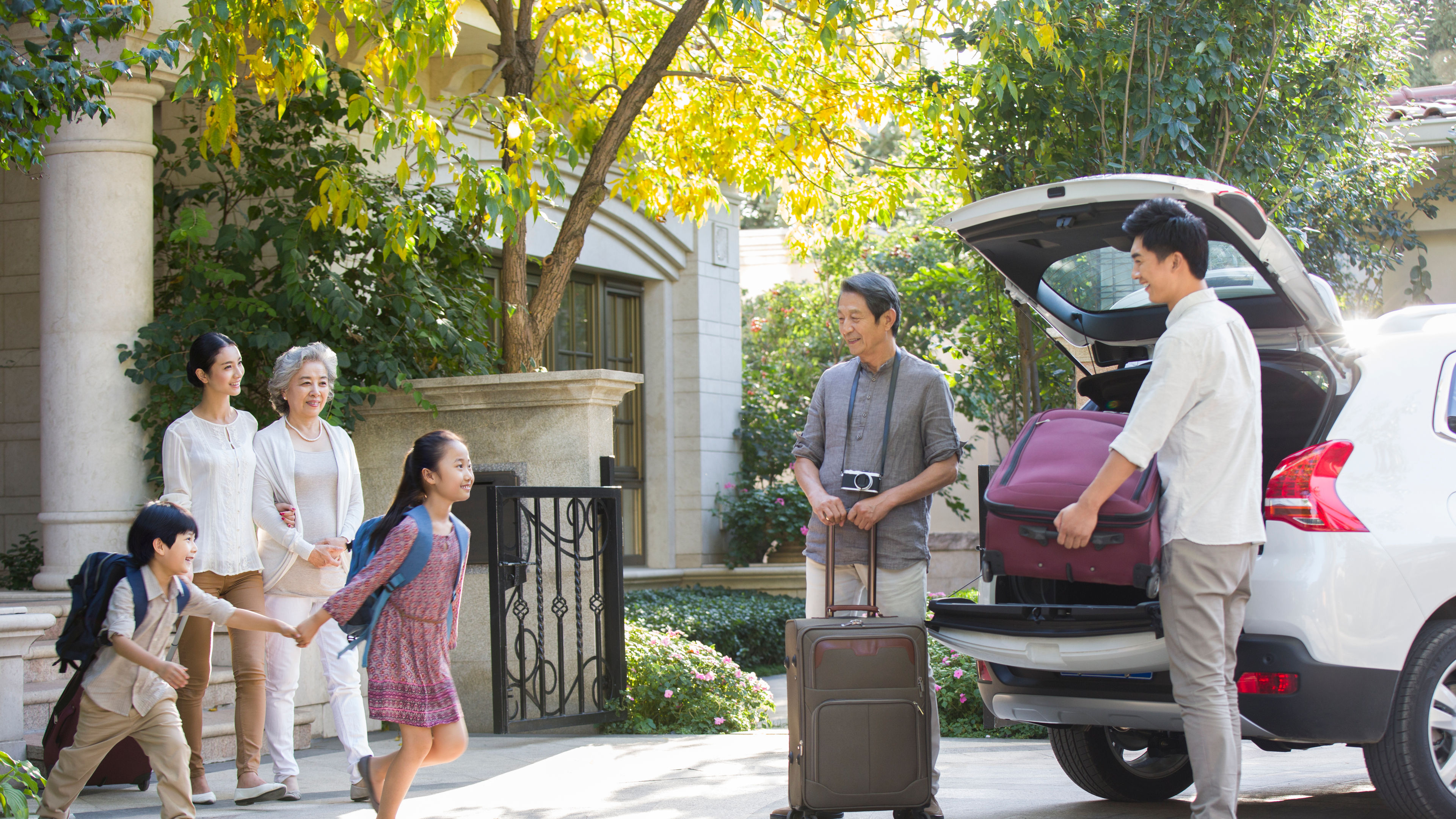 A family is packing their car with luggage and travel essentials for a road trip adventure. 