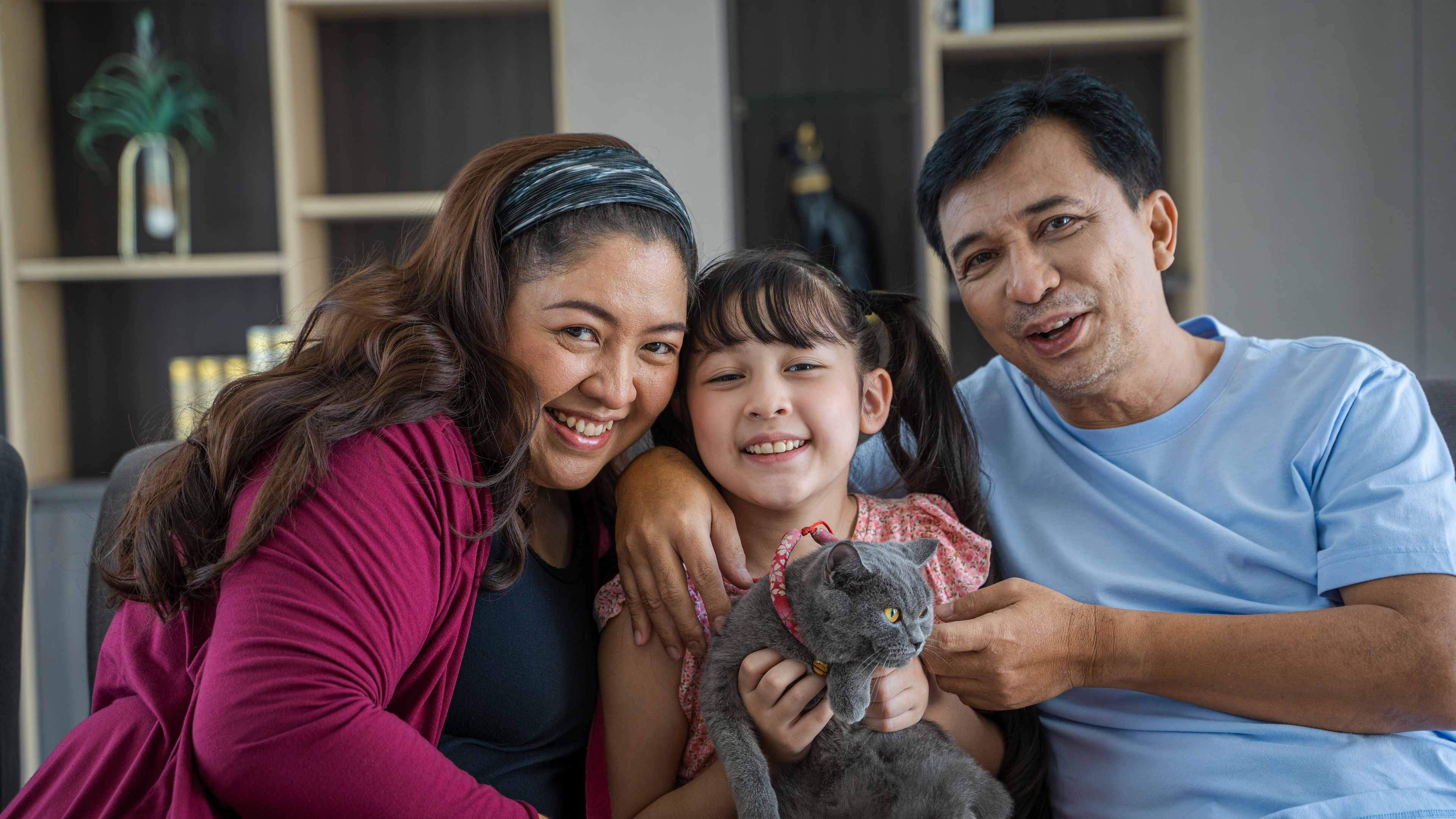 Father and mother playing with daughter and cats 