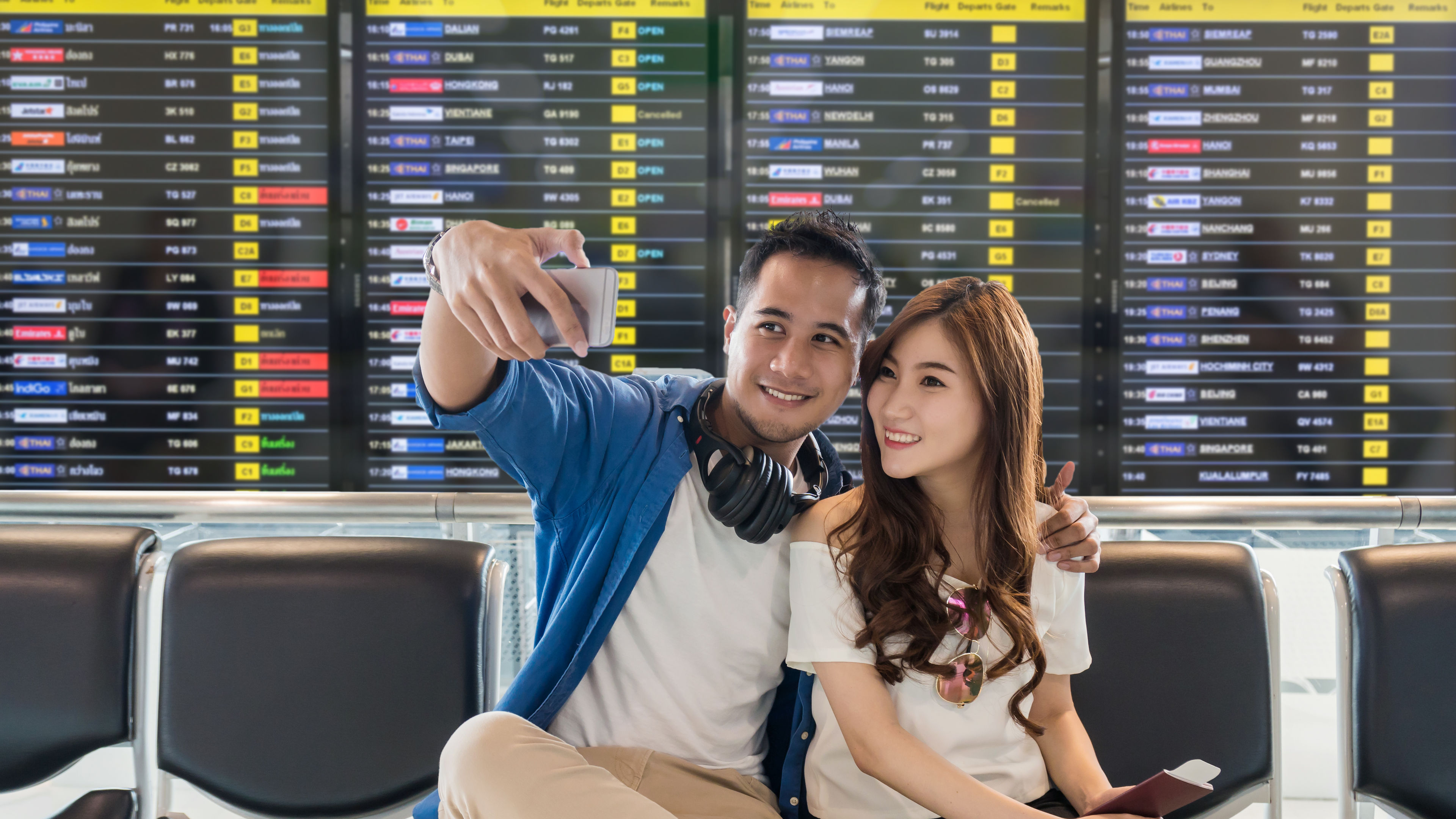 Picture of a happy traveller asian couple taling a selfie in the airport 