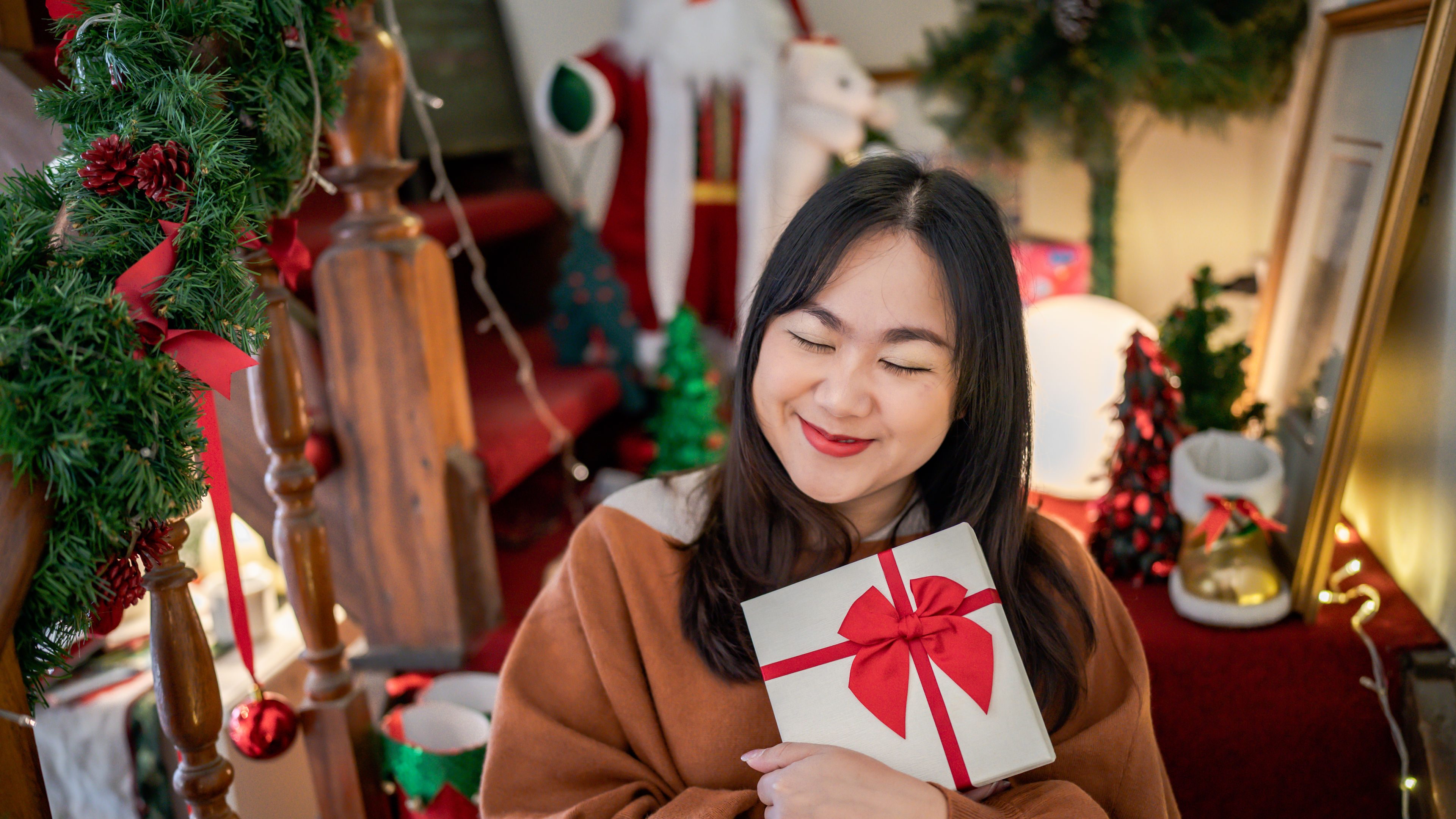 Happy asian woman hugging gift box. Receiving Christmas gift. 