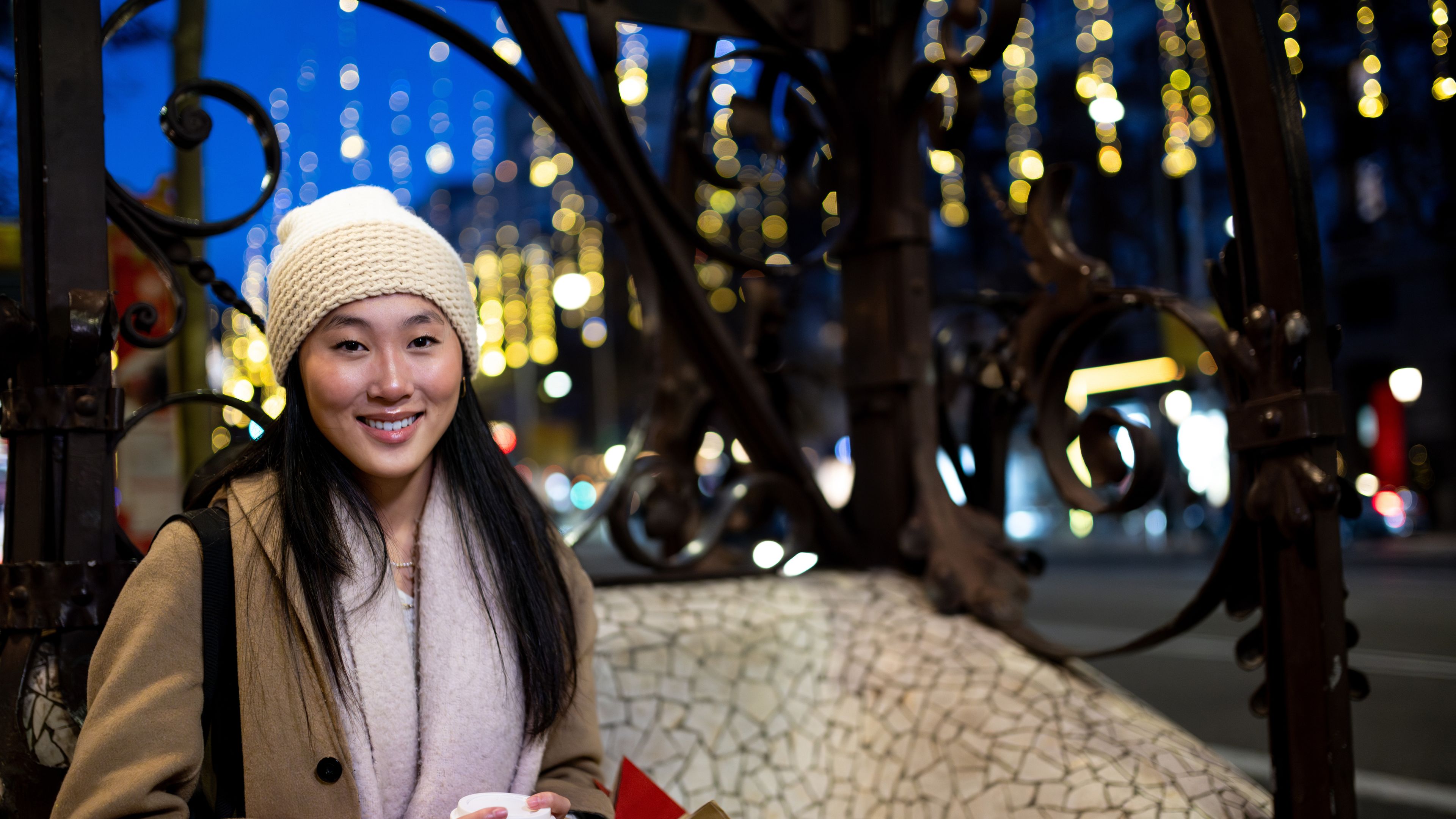 Joyful young woman shopping in the evening, looking at the camera.