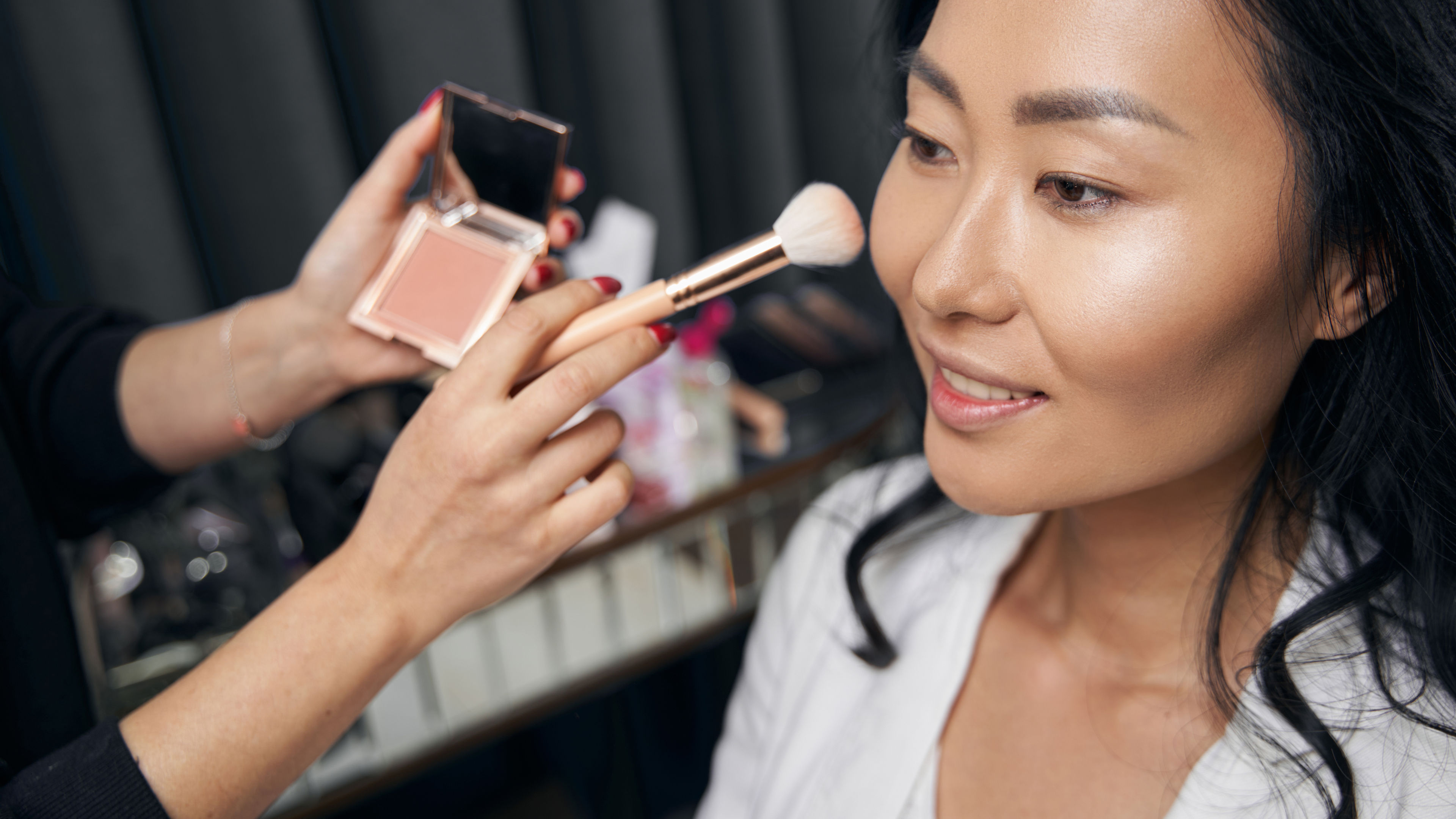 A picture of a lady applying highlighter on her face 