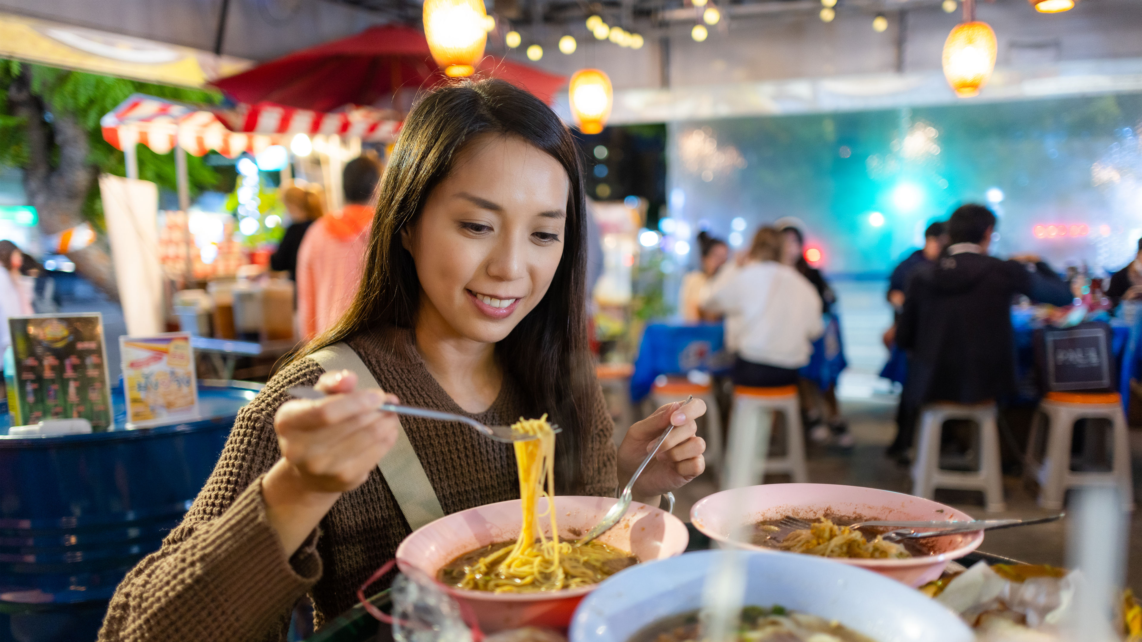 Image of a woman enjoying noodles in a restaurant