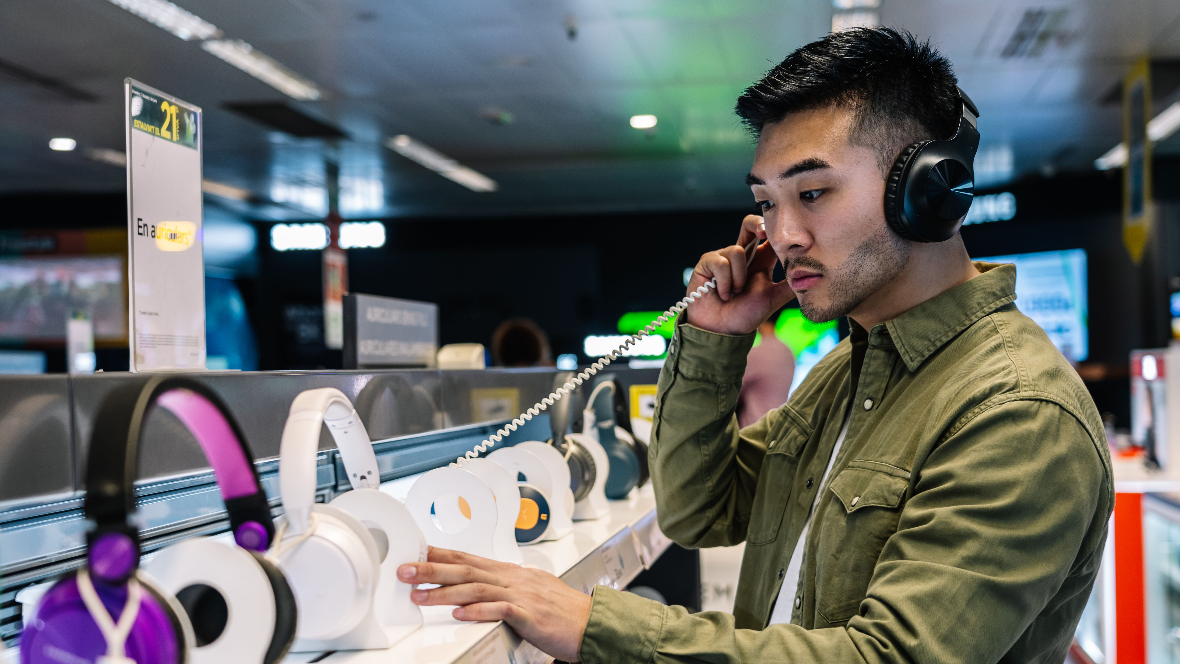 Man checking quality of modern headphones listening to music while shopping in mall 