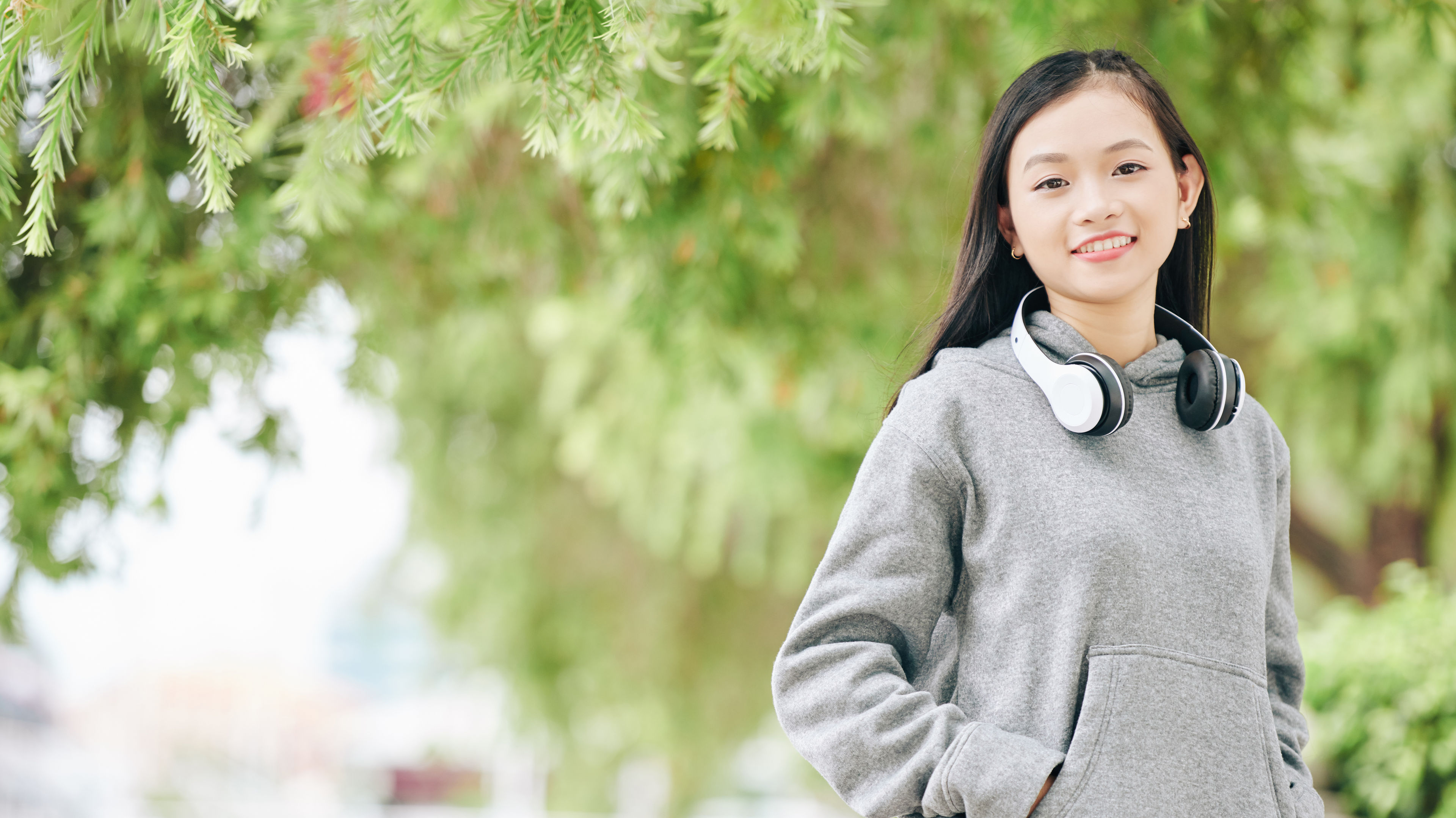 Portrait of cheerful Asian teenage girl in hoodie smiling.