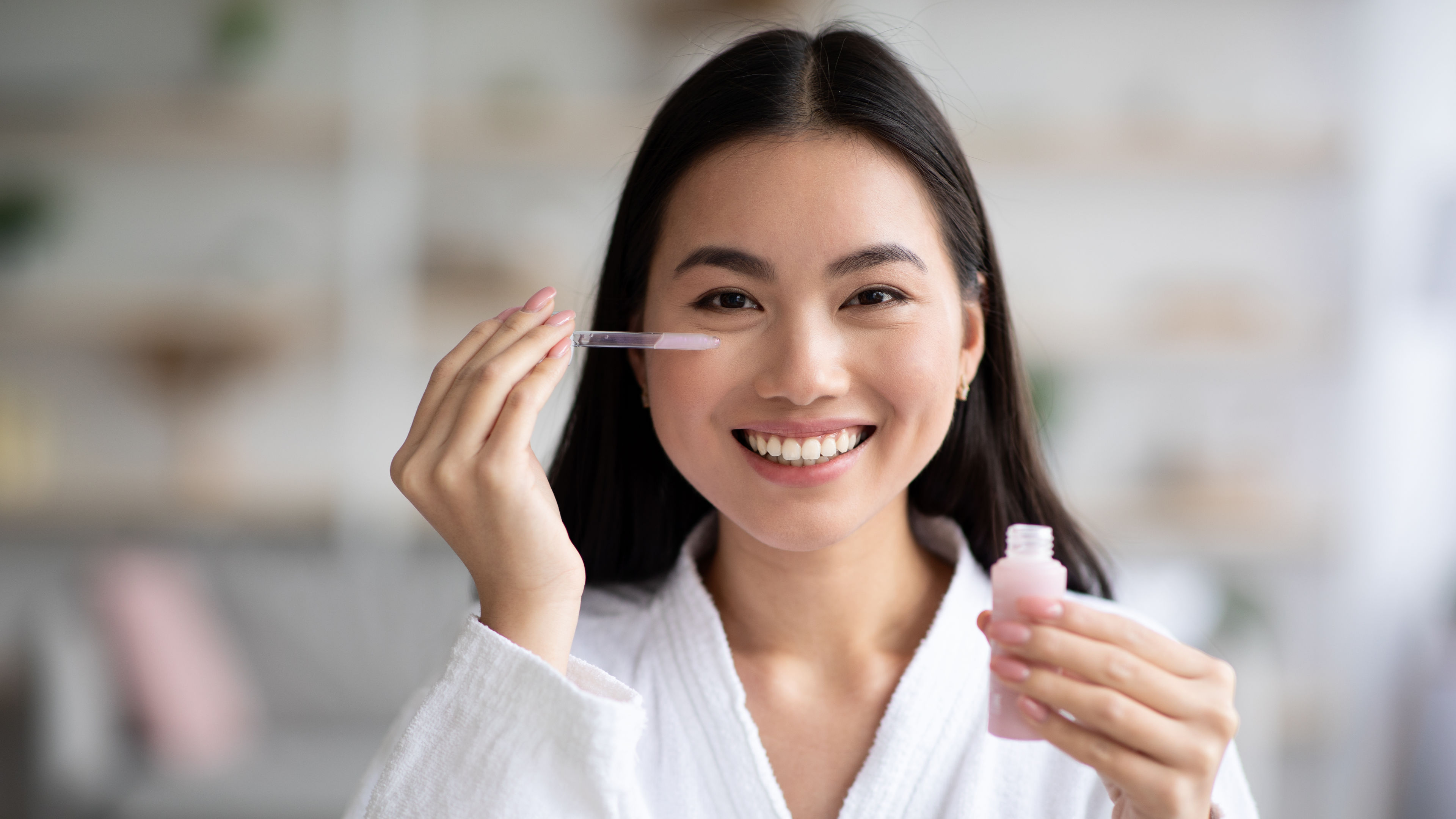 Pretty smiling lady applying serum and doing skincare 