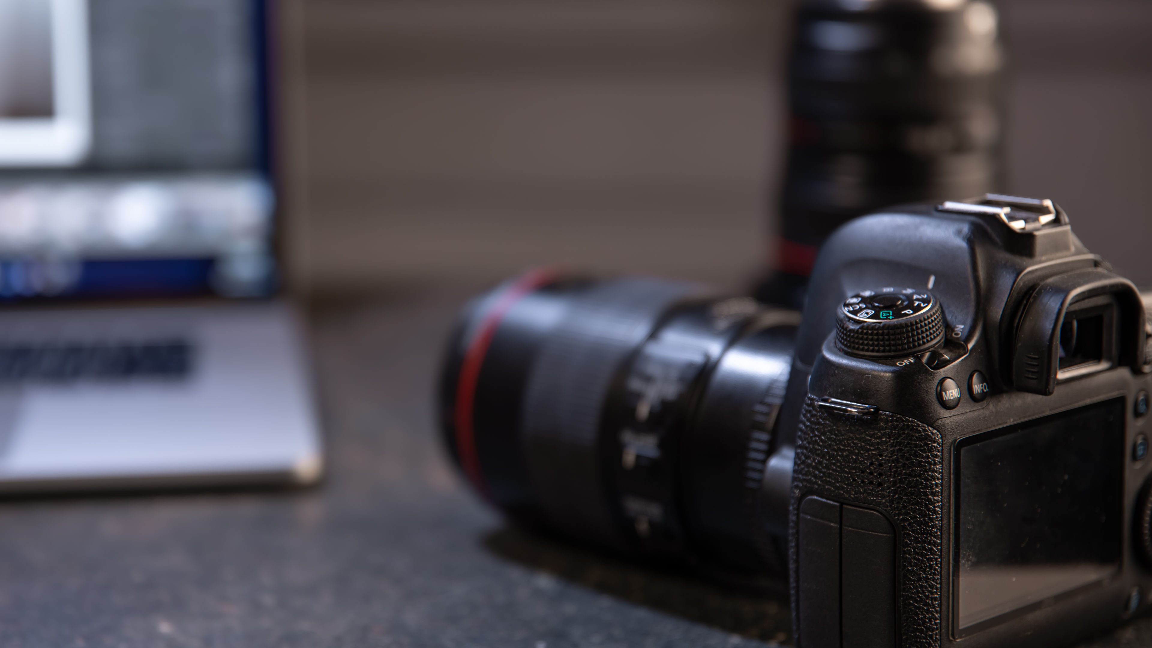 Professional camera on a blurred background with a laptop. The concept of working with photos and videos. 