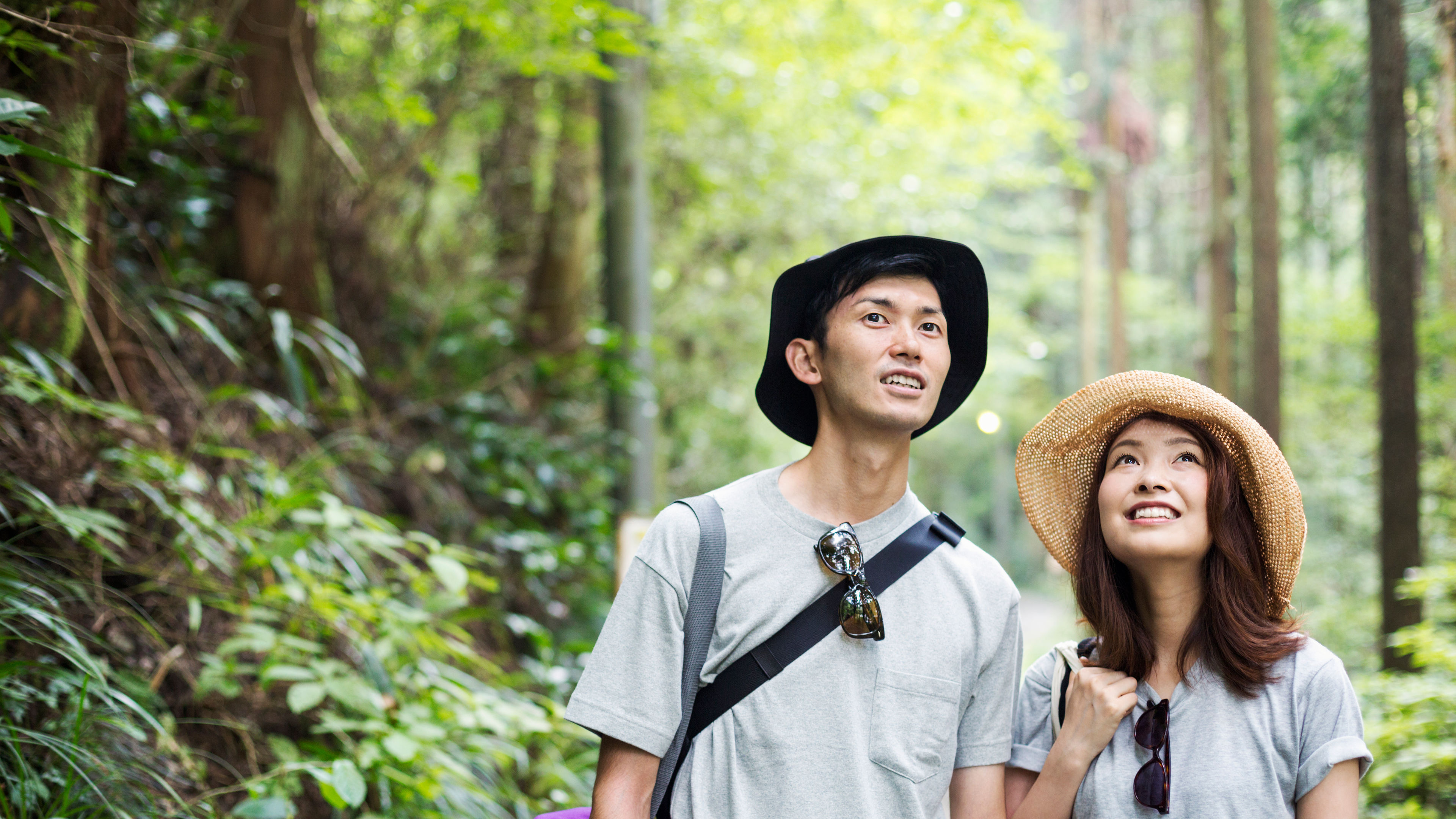 Smiling young woman and man standing in a forest. 