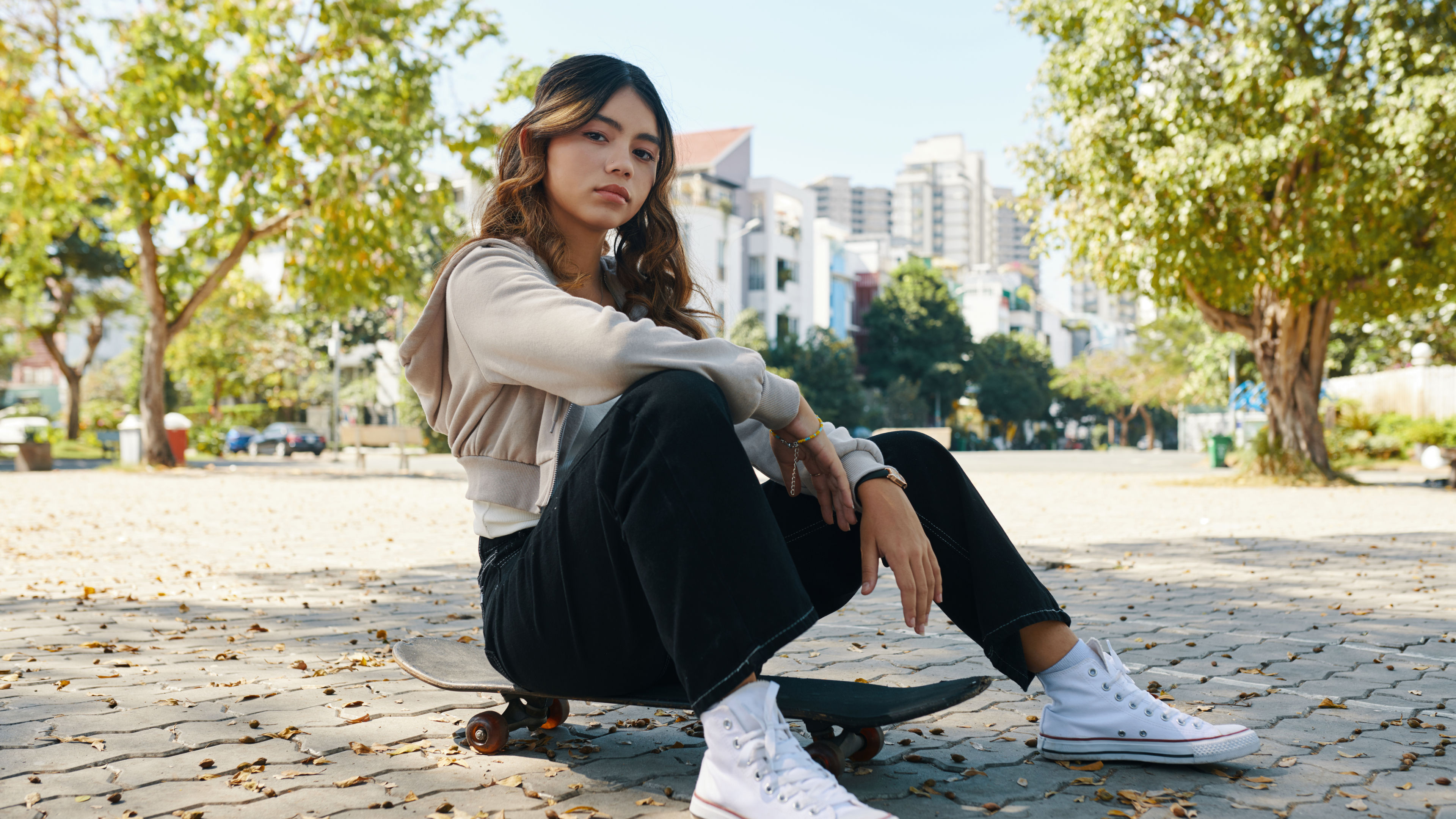 Teenage Girl Relaxing While Sitting on a Skateboard in an Urban Setting.