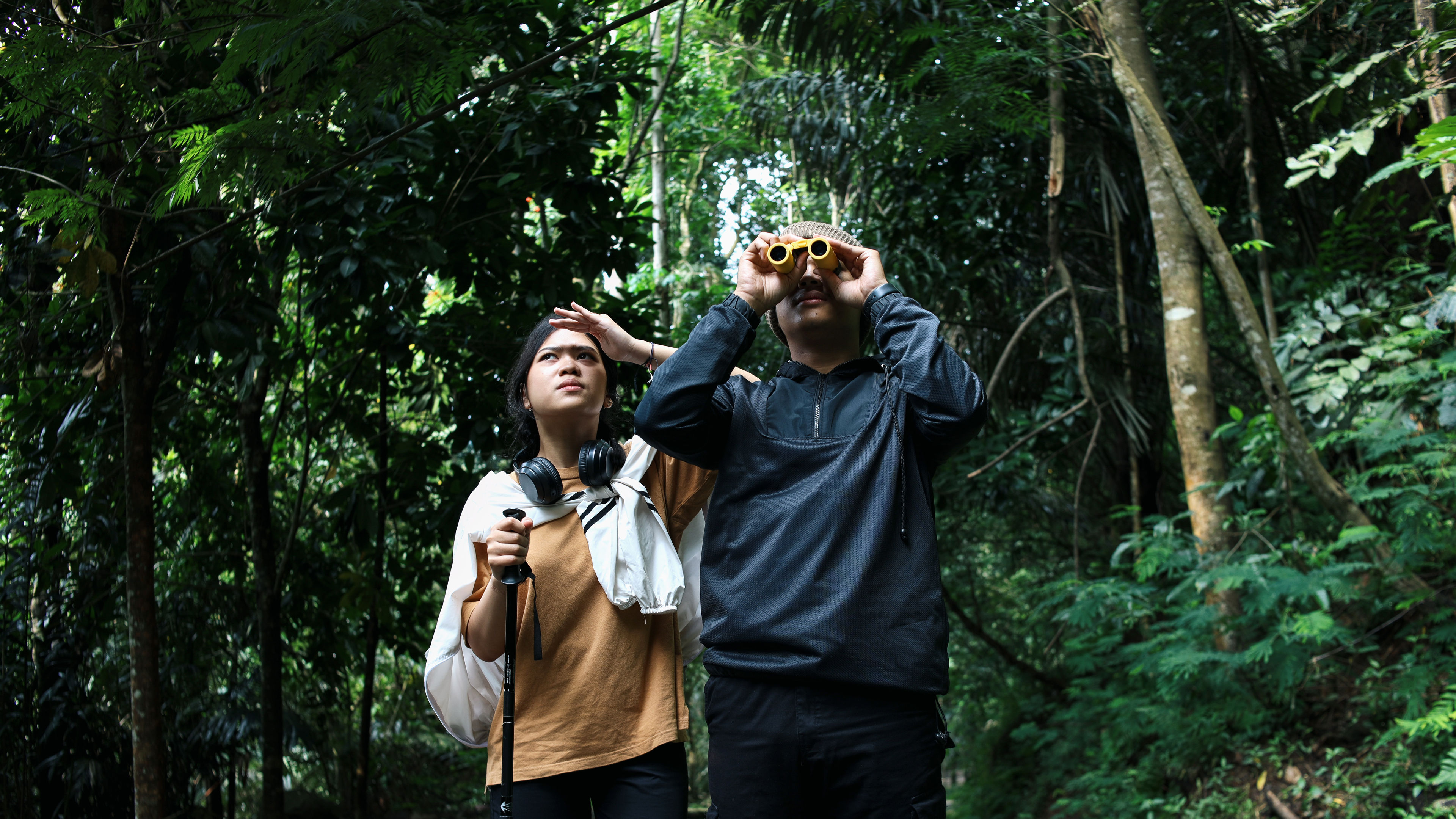 Two people are hiking in a dense green forest