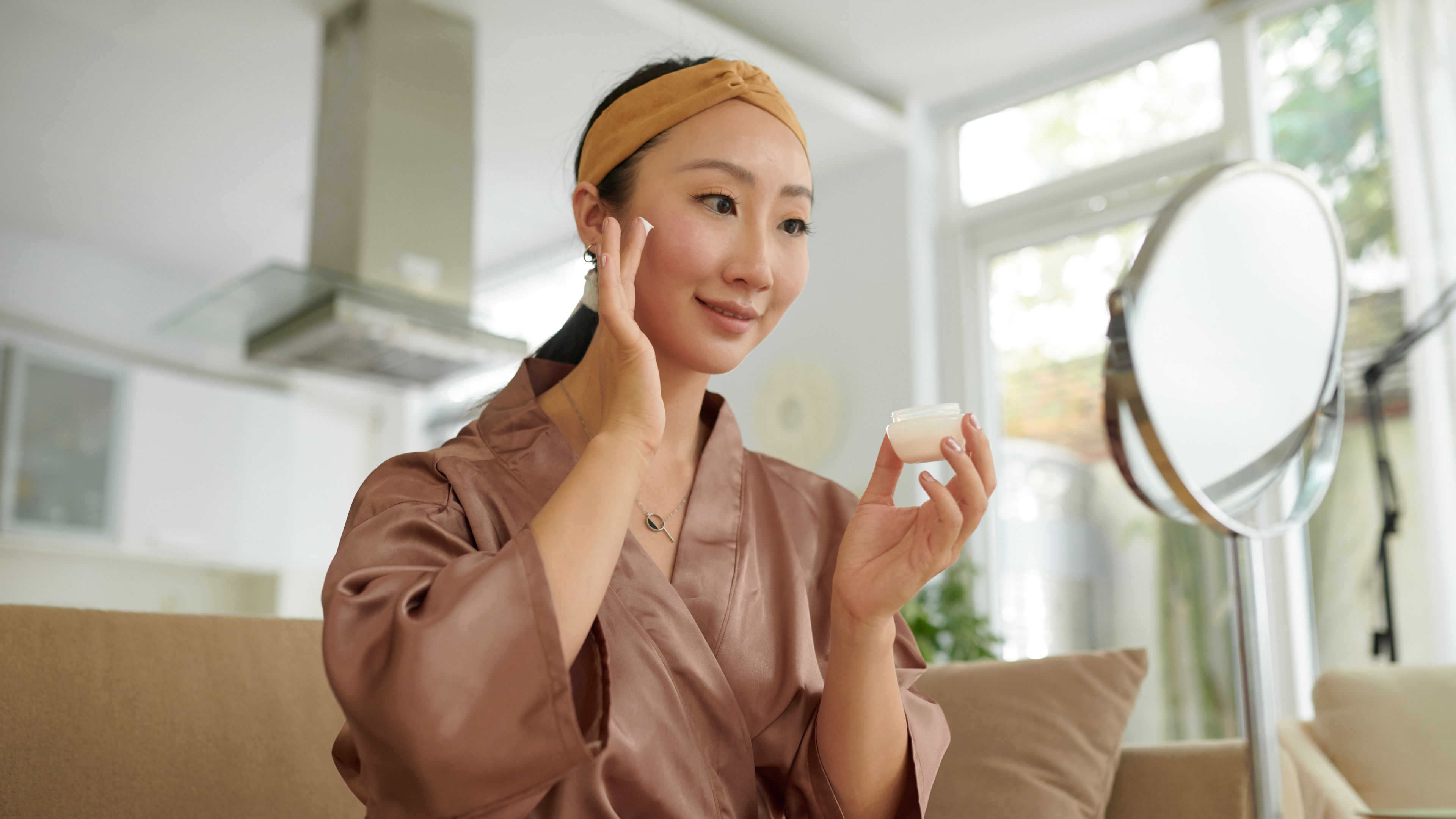 Woman applying anti ageing cream looking at the mirror 