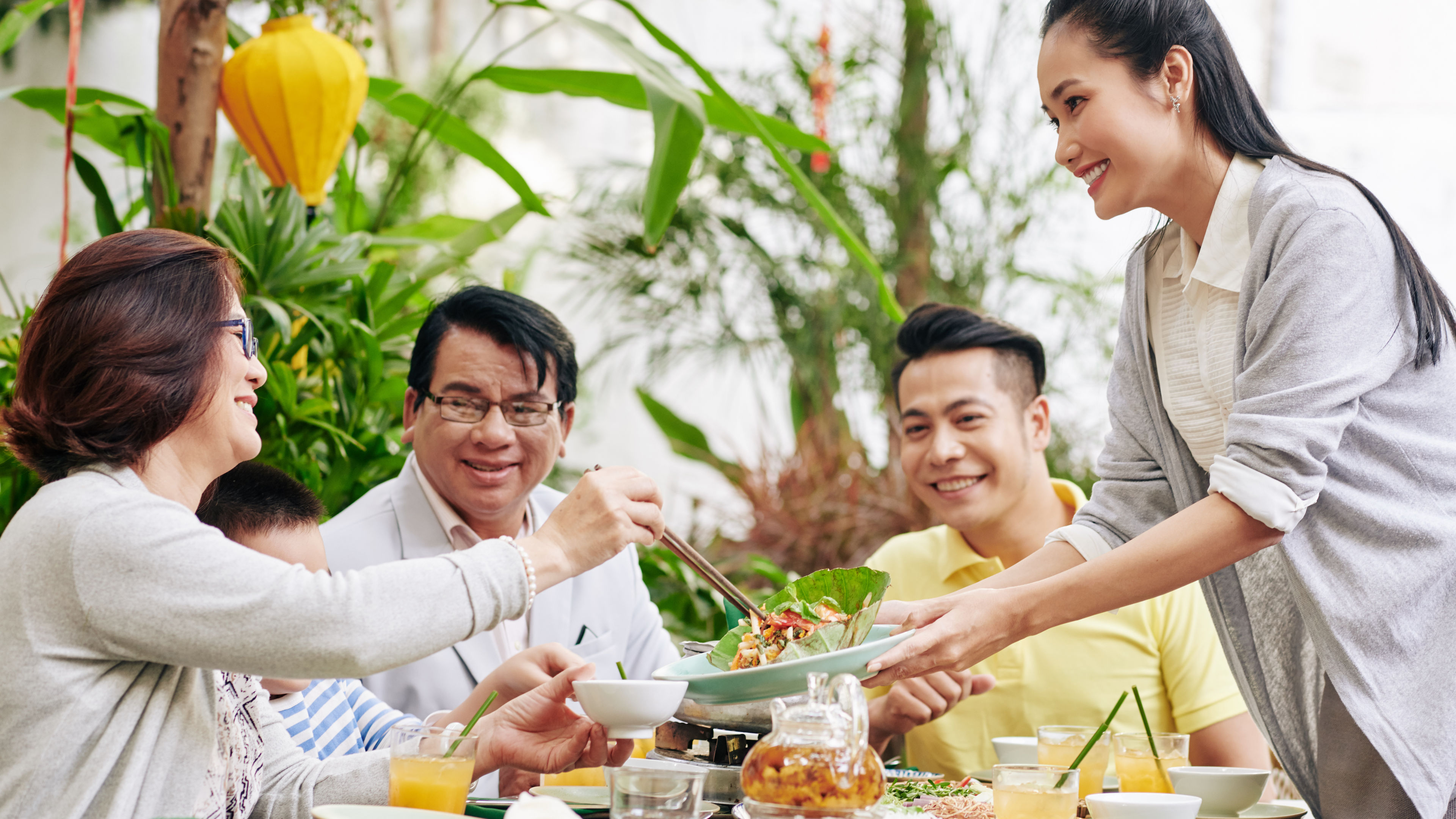 Picture of a woman offering food to a group of guests 