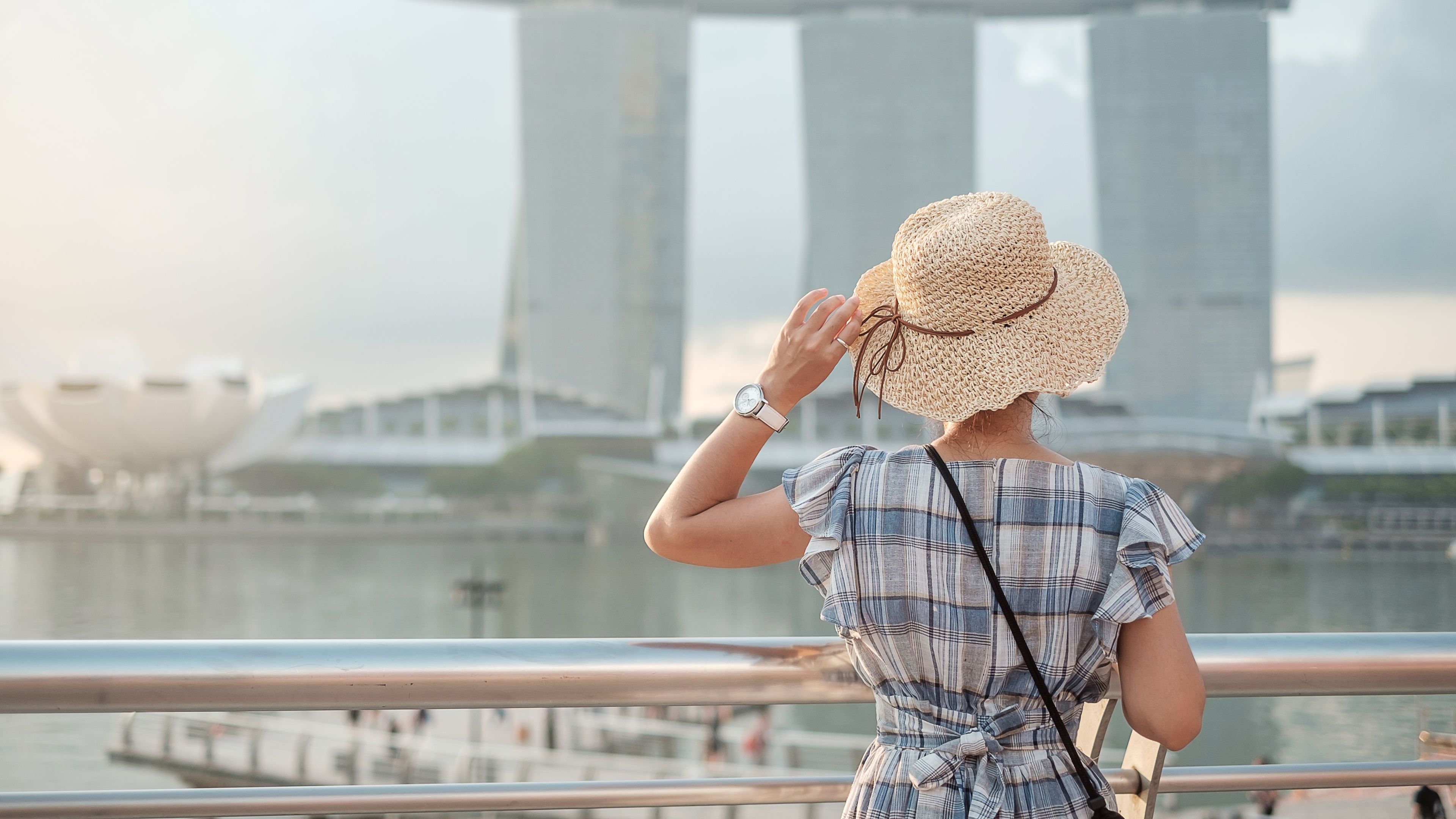 Woman traveling with hat in the morning, happy Asian traveler visit in Singapore city 