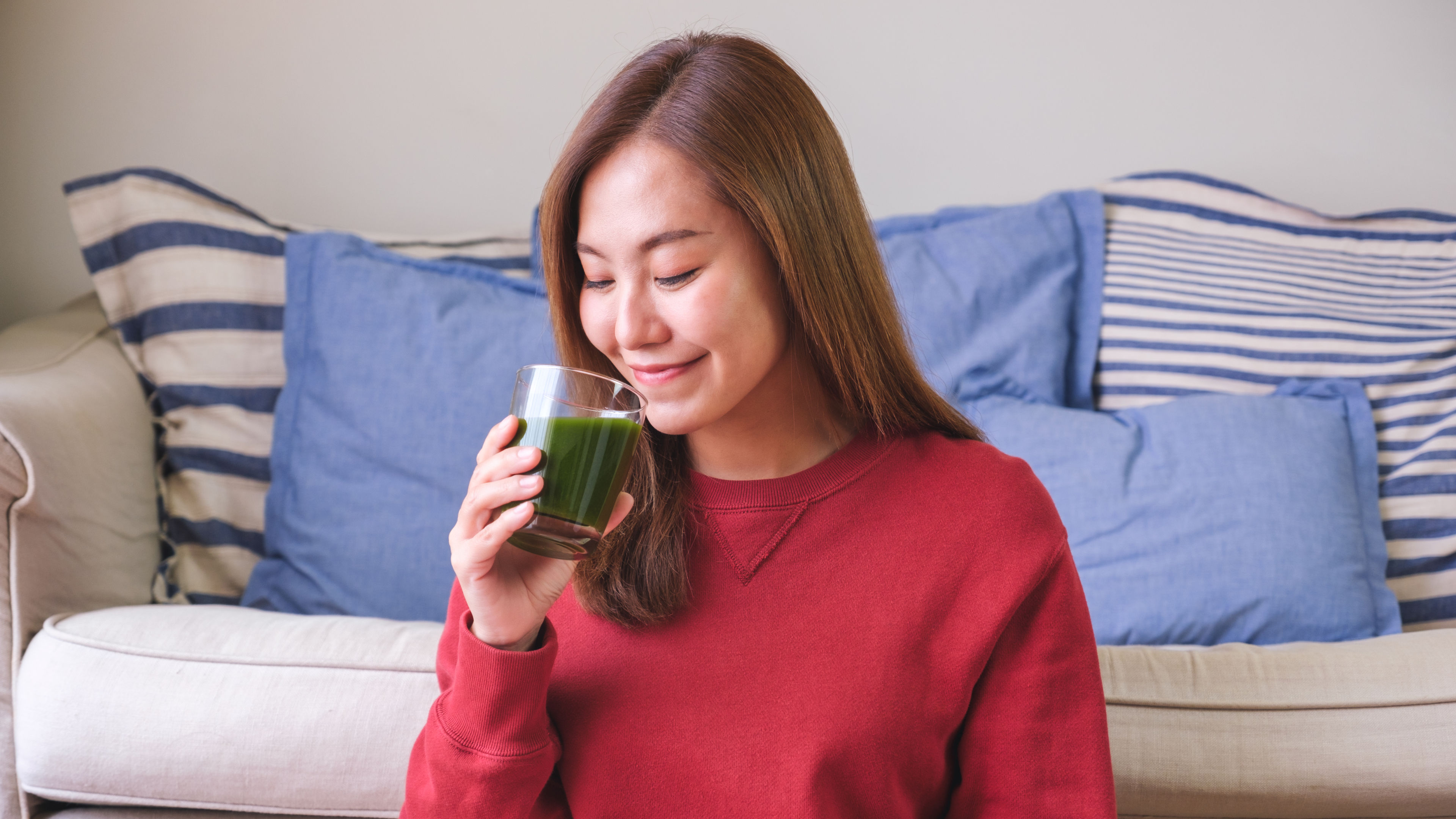 Image of a young woman drinking smoothie from a glass 